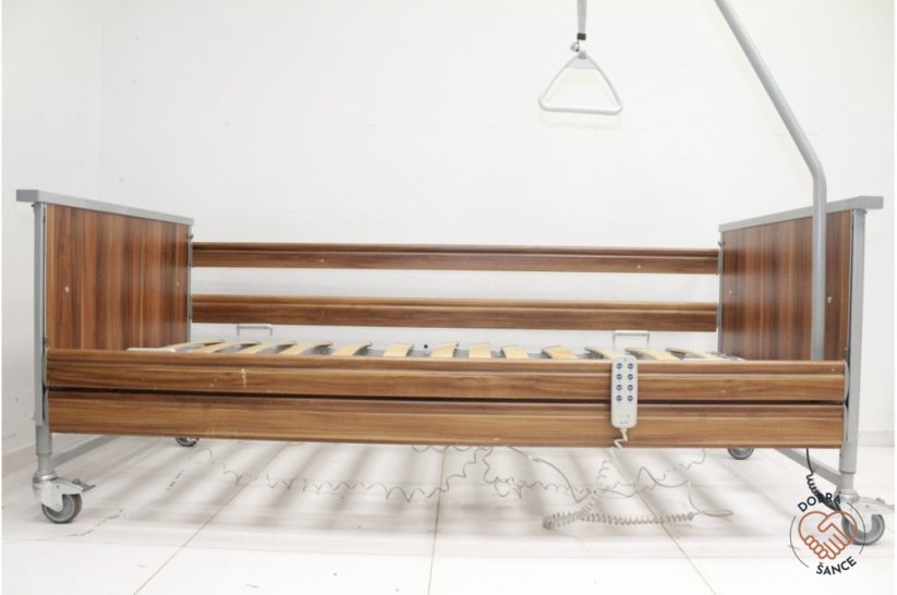 Elektrická postel Domiflex II s tmavým dřevěným obložením v nejnižší poloze pro snadný přístup