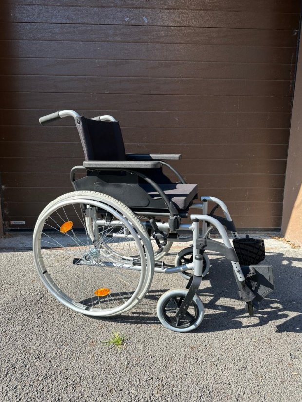 Repasovaný mechanický invalidní vozík venku, boční pohled, skládací konstrukce, plná kola a stabilní rám