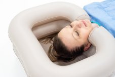 Nafukovací umyvadlo se sprchou v akci, žena si pohodlně pokládá hlavu při mytí vlasů v posteli